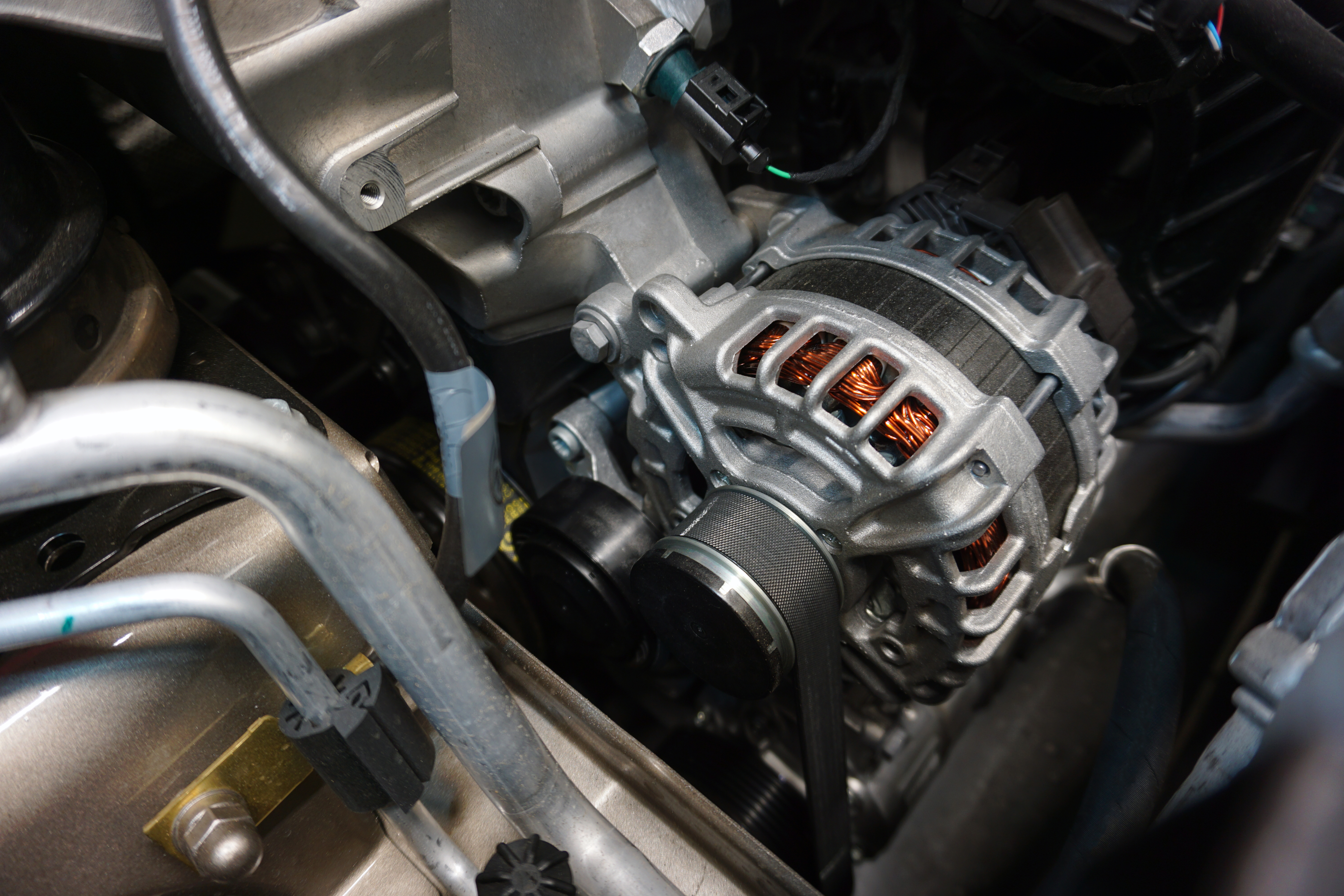 Close-up of a vehicle's alternator, showcasing detailed repairs and replacement services, including starter motor repairs.